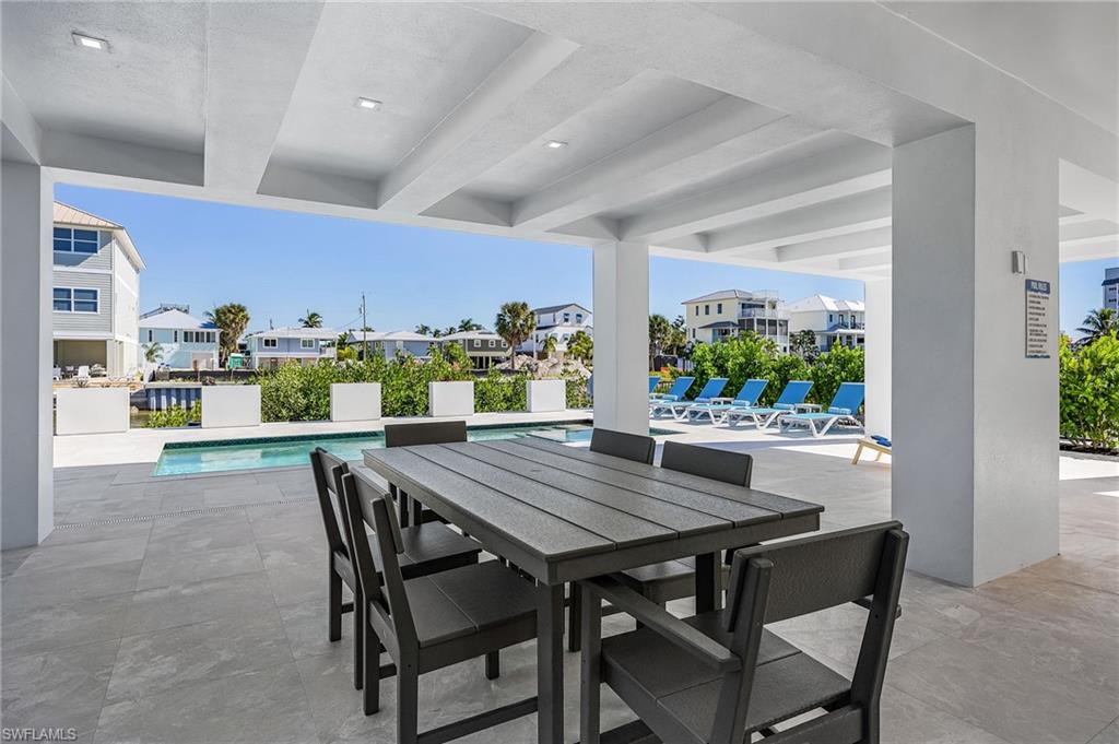 View of patio with a community pool, a residential view, and outdoor dining area - Virtually Edited Image