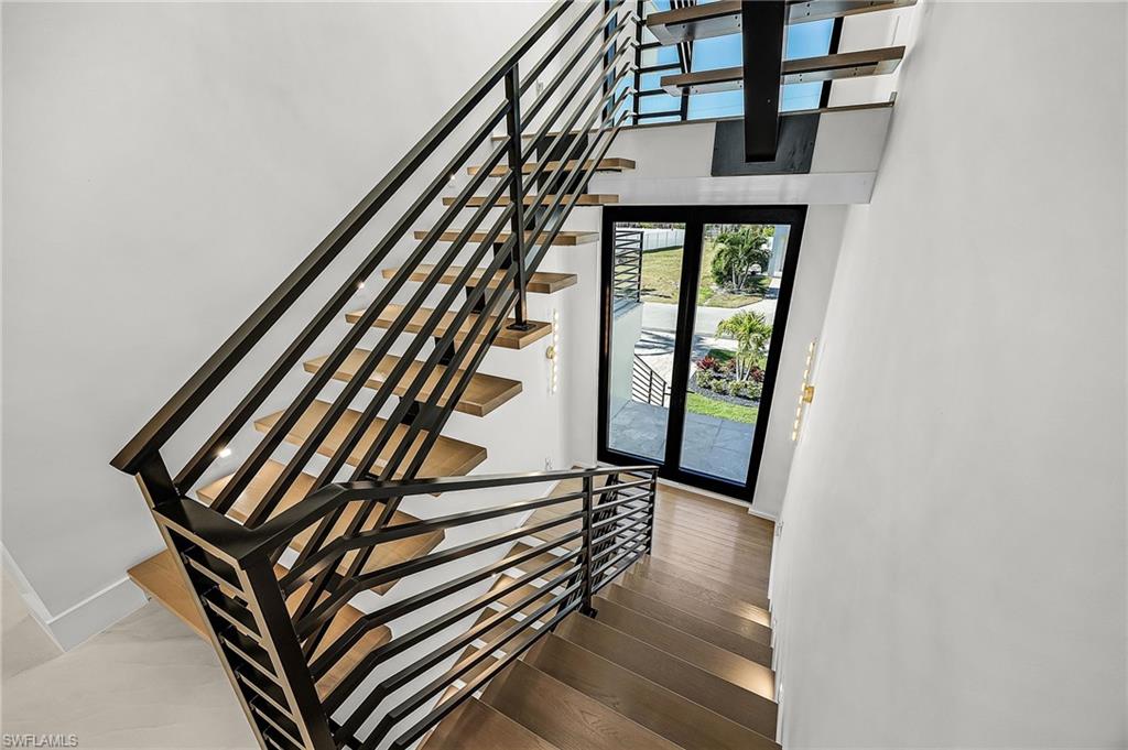 Staircase with hardwood / wood-style flooring and a towering ceiling - Virtually Edited Image