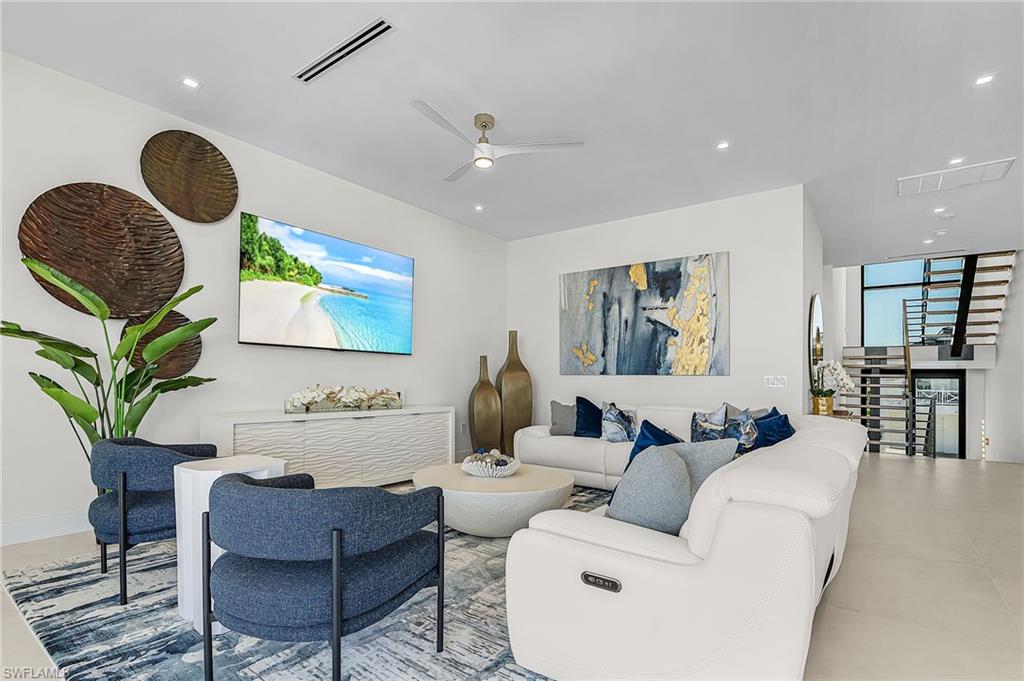 Living room featuring ceiling fan, floor to ceiling windows, and recessed lighting - Virtually Edited Image