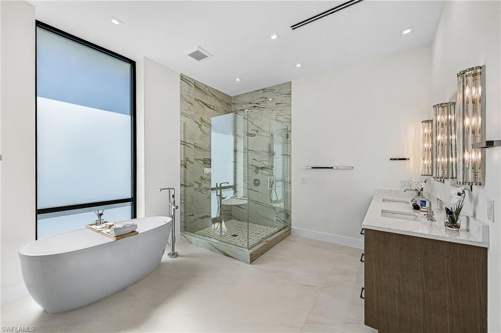 Full bath featuring double vanity, a freestanding bath, and a marble finish shower - Virtually Edited Image