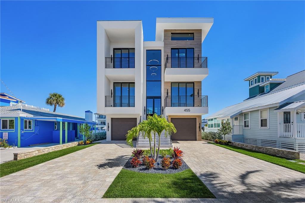 Contemporary house featuring stucco siding, decorative driveway, an attached garage, and a balcony - Virtually Edited Image