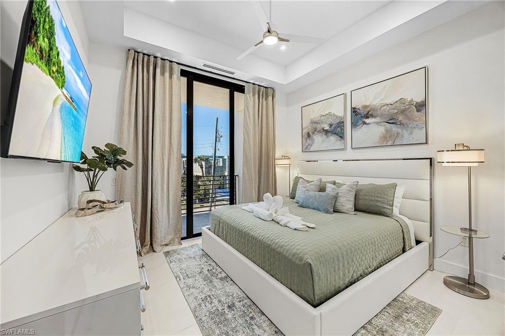Bedroom with access to exterior, a ceiling fan, and a tray ceiling - Virtually Edited Image