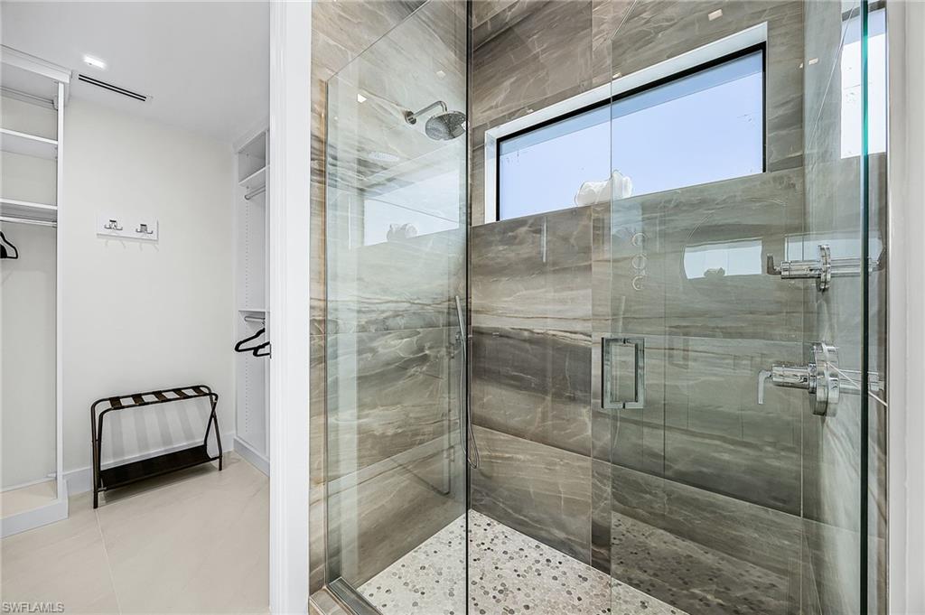 Bathroom featuring a stall shower, tile patterned floors, and a spacious closet - Virtually Edited Image