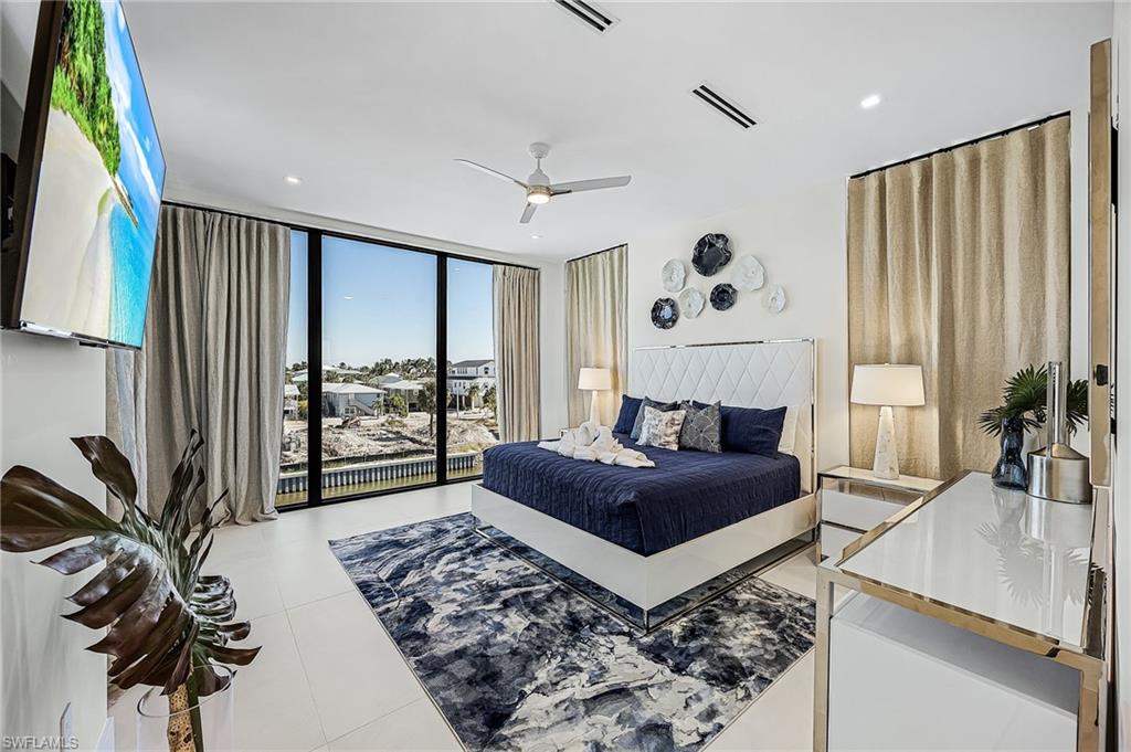 Bedroom featuring expansive windows, a ceiling fan, and light tile patterned floors - Virtually Edited Image