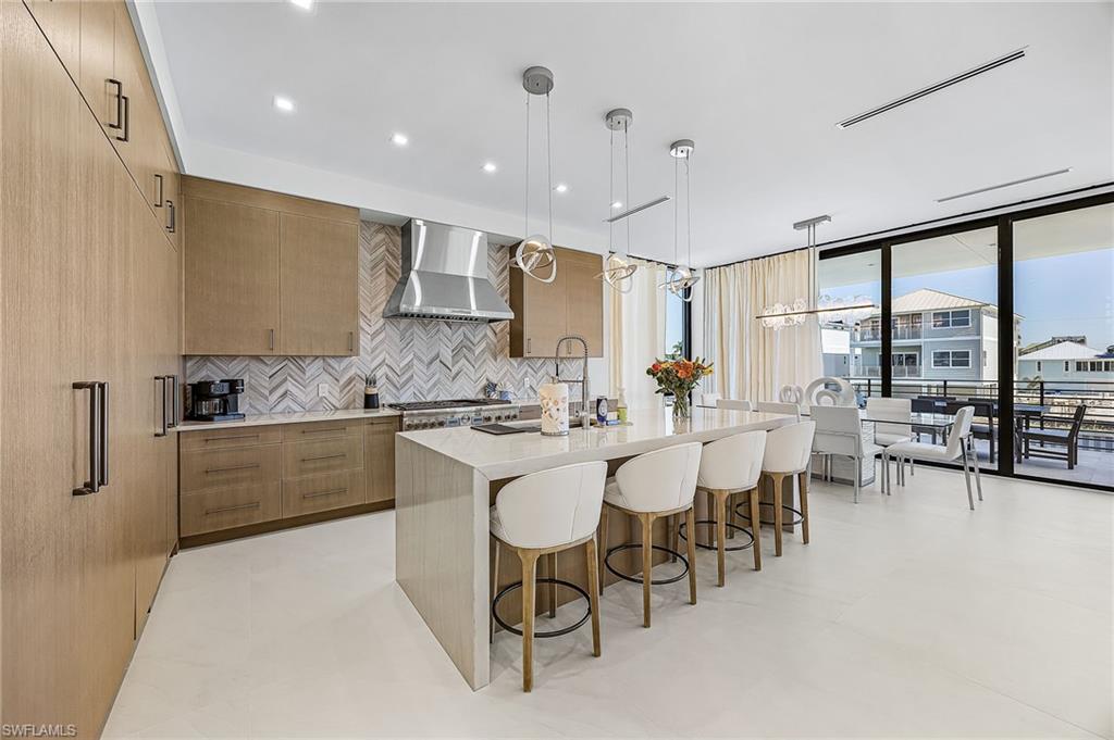 Kitchen with modern cabinets, light stone counters, decorative light fixtures, decorative backsplash, and floor to ceiling windows - Virtually Edited Image