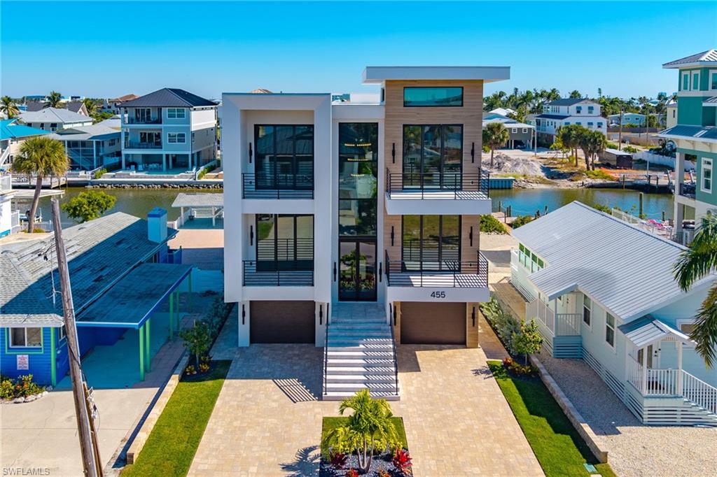 Contemporary house with a residential view, a balcony, a water view, and an attached garage - Virtually Edited Image