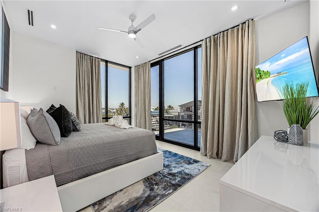 Bedroom with floor to ceiling windows, access to exterior, and ceiling fan - Virtually Edited Image