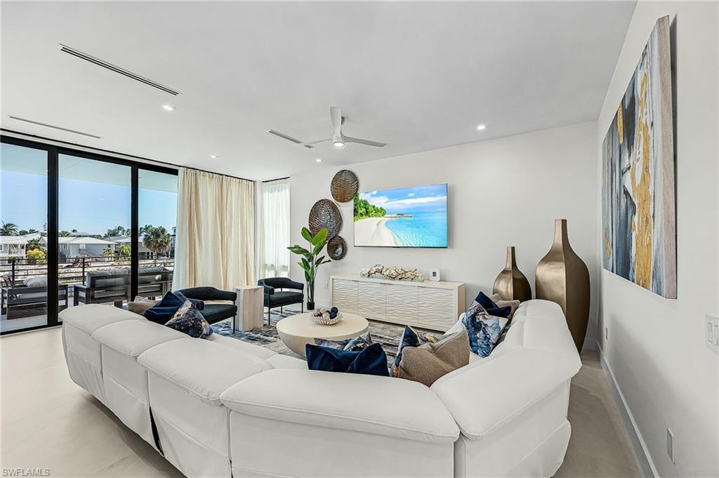 Living room featuring floor to ceiling windows, recessed lighting, and a ceiling fan - Virtually Edited Image