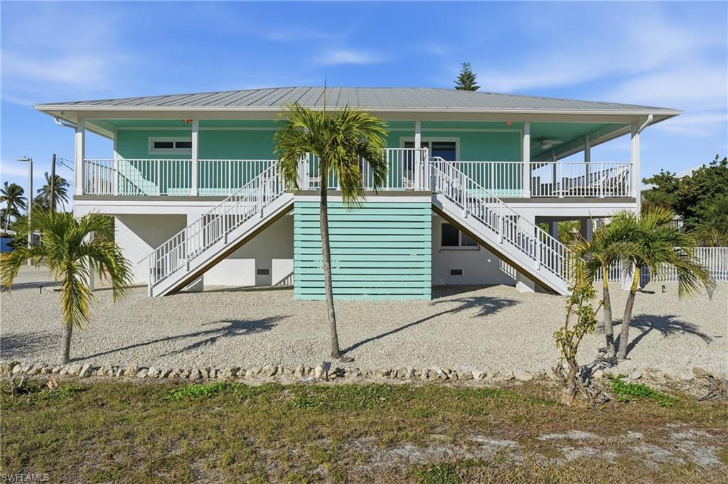 View of front of home featuring stairway, a porch, and a metal roof - Virtually Edited Image
