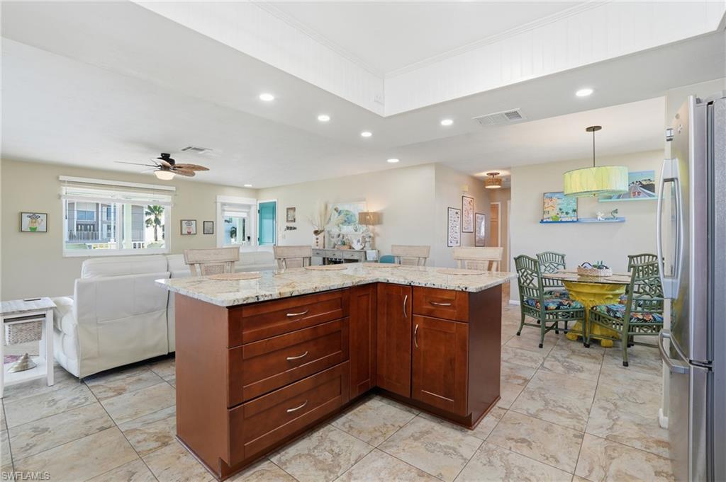 Kitchen with recessed lighting, freestanding refrigerator, open floor plan, a kitchen island, and hanging light fixtures - Virtually Edited Image