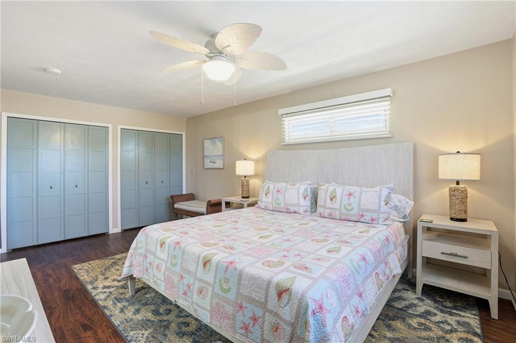 Bedroom with multiple closets, dark wood-style floors, and a ceiling fan - Virtually Edited Image - Virtually Edited Image