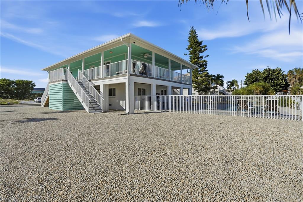 Rear view of property with ceiling fan, stairway, and covered porch - Virtually Edited Image