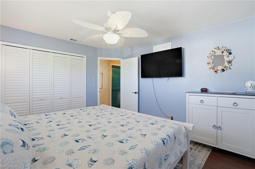 Bedroom featuring ceiling fan, a closet, and dark wood-style flooring - Virtually Edited Image
