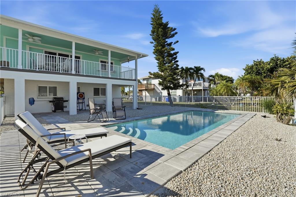 View of pool featuring a patio area, a grill, and a balcony - Virtually Edited Image