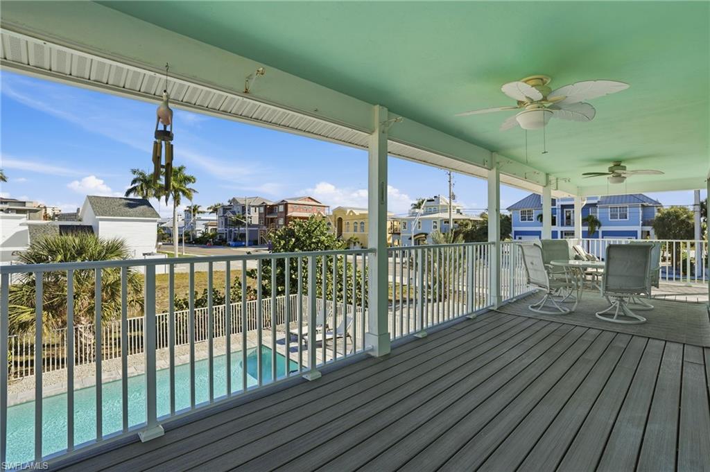 Wooden terrace with a residential view, ceiling fan, outdoor dining space, and a sunroom - Virtually Edited Image