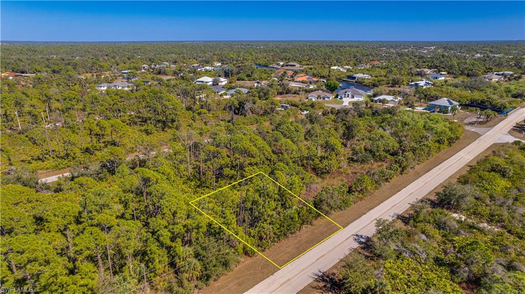 Aerial view of residential area with a forest and property parcel outlined