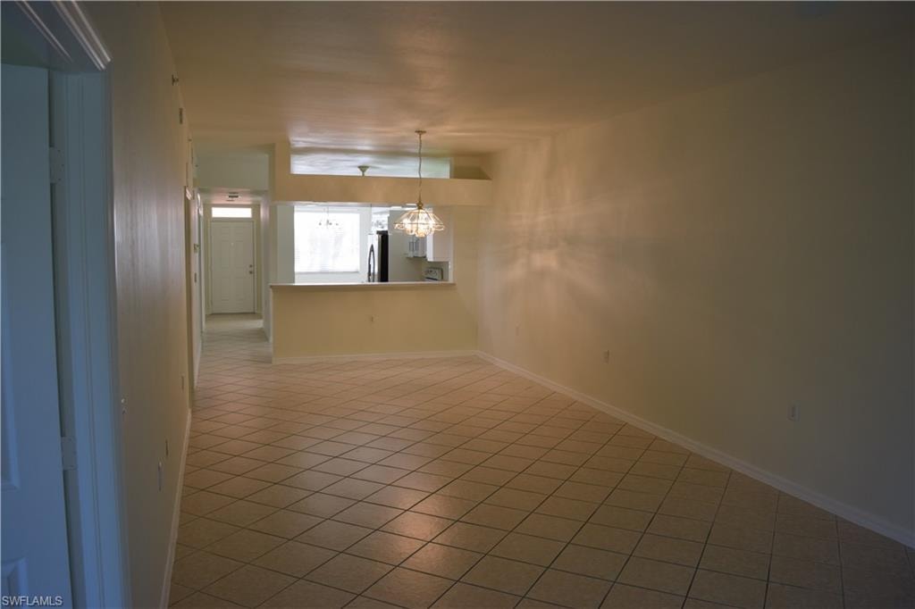 Empty room featuring light tile patterned floors and a chandelier