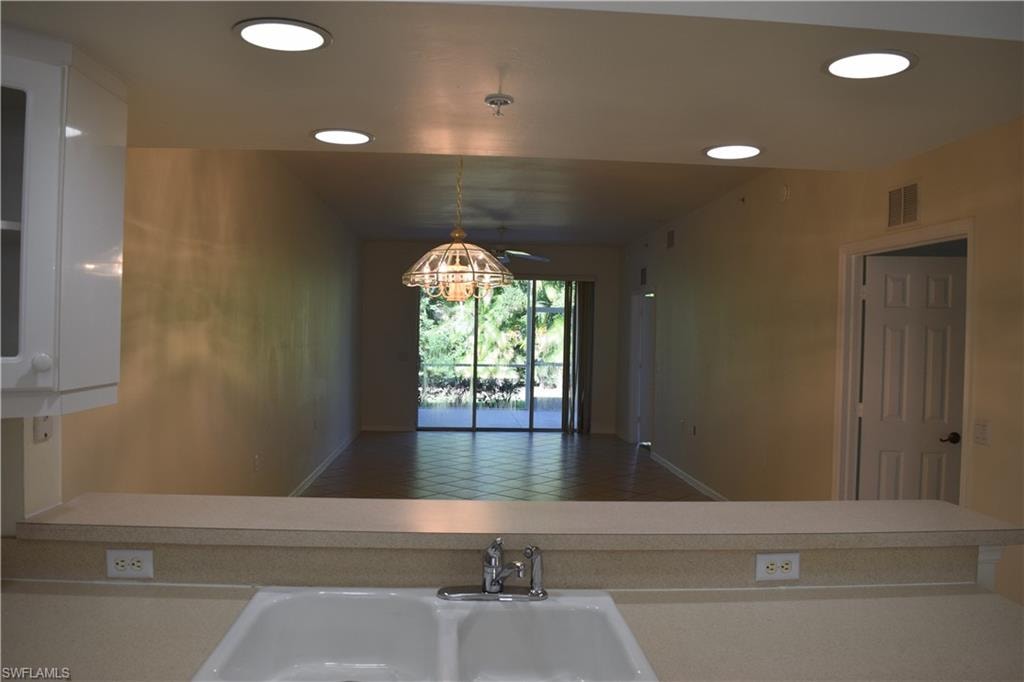 Kitchen featuring light countertops, hanging light fixtures, recessed lighting, white cabinets, and open floor plan