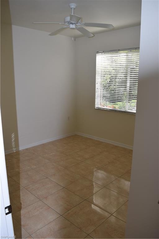 Empty room with ceiling fan and light tile patterned flooring
