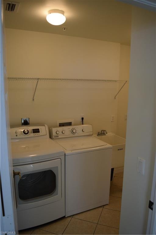 Laundry area with light tile patterned floors and washer and clothes dryer