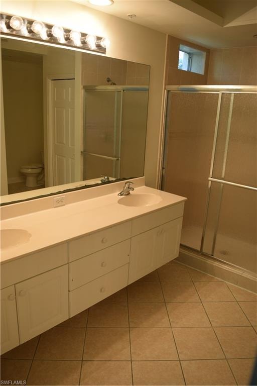 Bathroom with a shower stall, double vanity, and light tile patterned floors