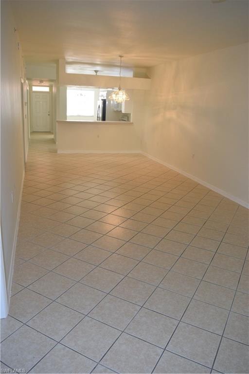 Empty room featuring baseboards and light tile patterned floors