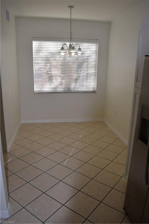 Unfurnished dining area with light tile patterned flooring and a chandelier