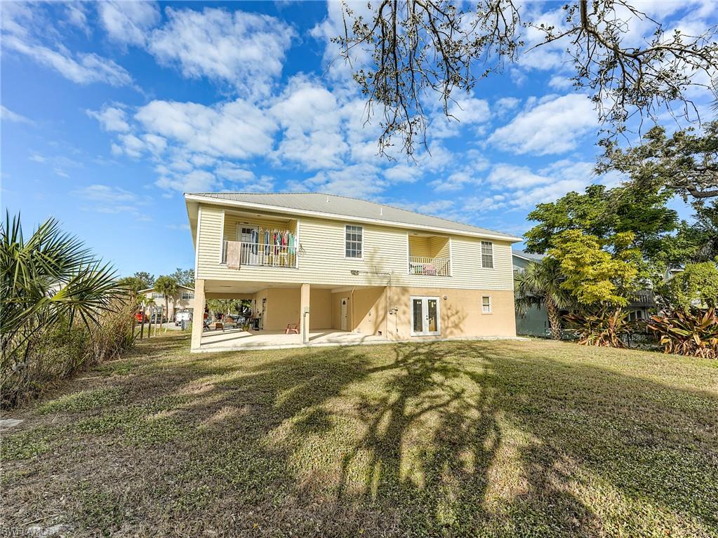 Back of house featuring a patio area, a lawn, and a balcony
