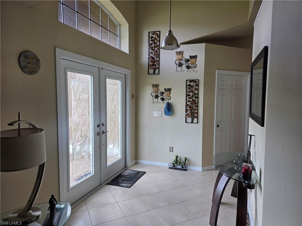 Entrance foyer featuring french doors, light tile floors, and a towering ceiling