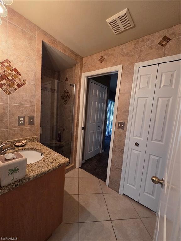 Full bathroom featuring tile walls, a shower stall, light tile floors, and vanity