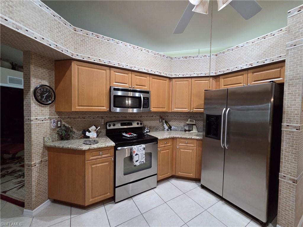 Kitchen featuring appliances with stainless steel finishes, tile backsplash, light tile floors, and light granite countertops