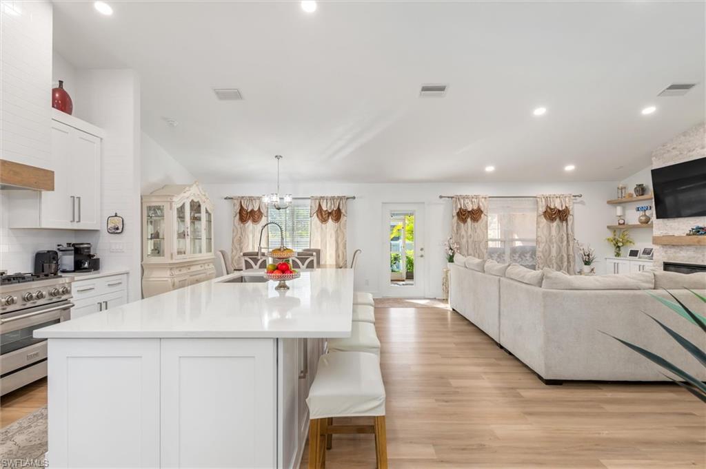 Kitchen featuring white cabinetry, open floor plan, a kitchen breakfast bar, a kitchen island with sink, and high end stainless steel range oven