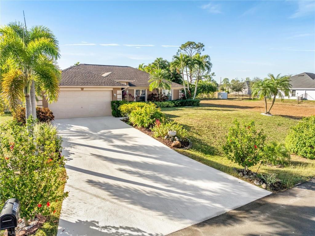 Ranch-style house featuring concrete driveway, a front yard, and a garage