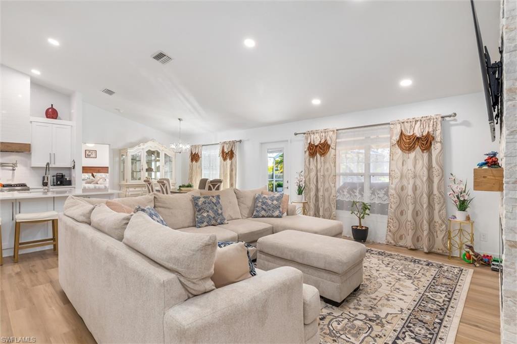 Living area with light wood-type flooring, a chandelier, vaulted ceiling, and recessed lighting