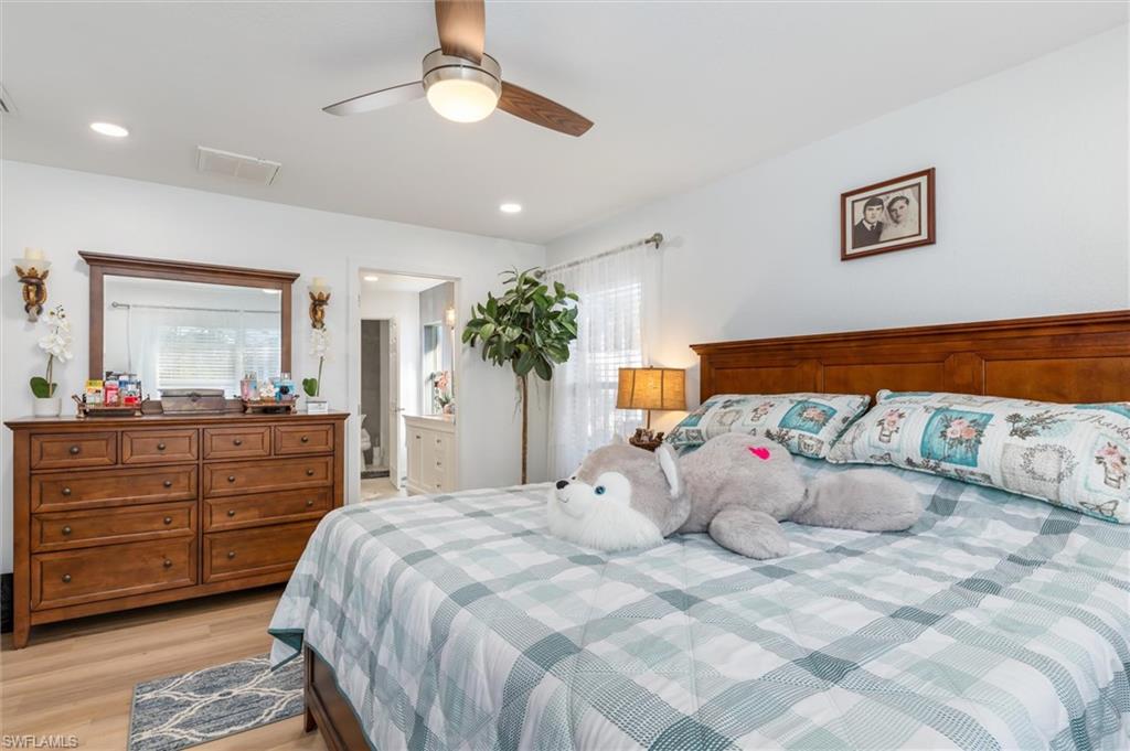 Bedroom with light wood finished floors, multiple windows, ceiling fan, ensuite bathroom, and recessed lighting