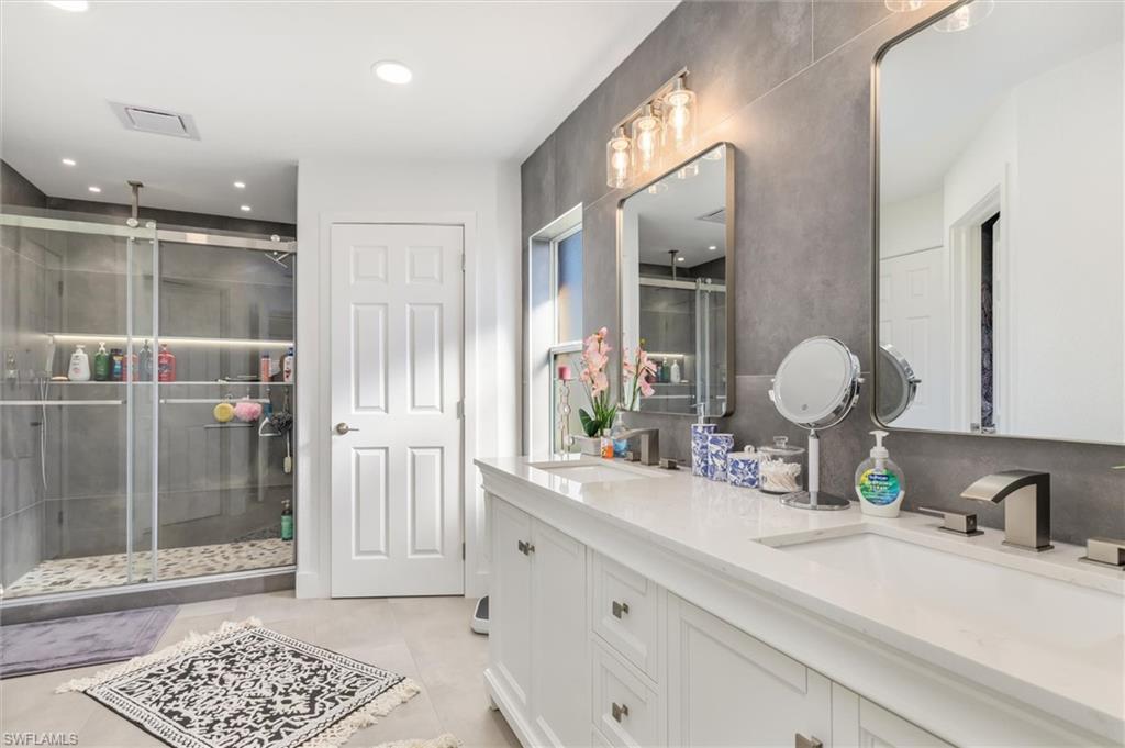 Full bath featuring double vanity, a shower stall, and recessed lighting