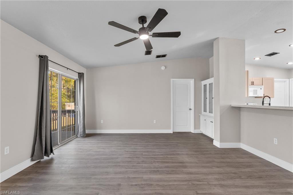 Unfurnished living room featuring dark wood finished floors, a ceiling fan, and vaulted ceiling