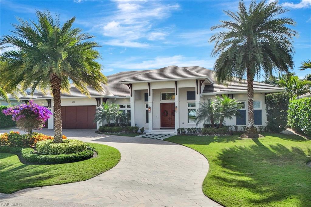 View of front of property featuring decorative driveway, a front yard, a tile roof, an attached garage, and stucco siding