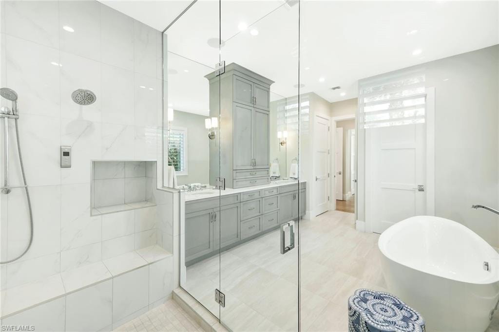 Bathroom with double vanity, a soaking tub, and a stall shower