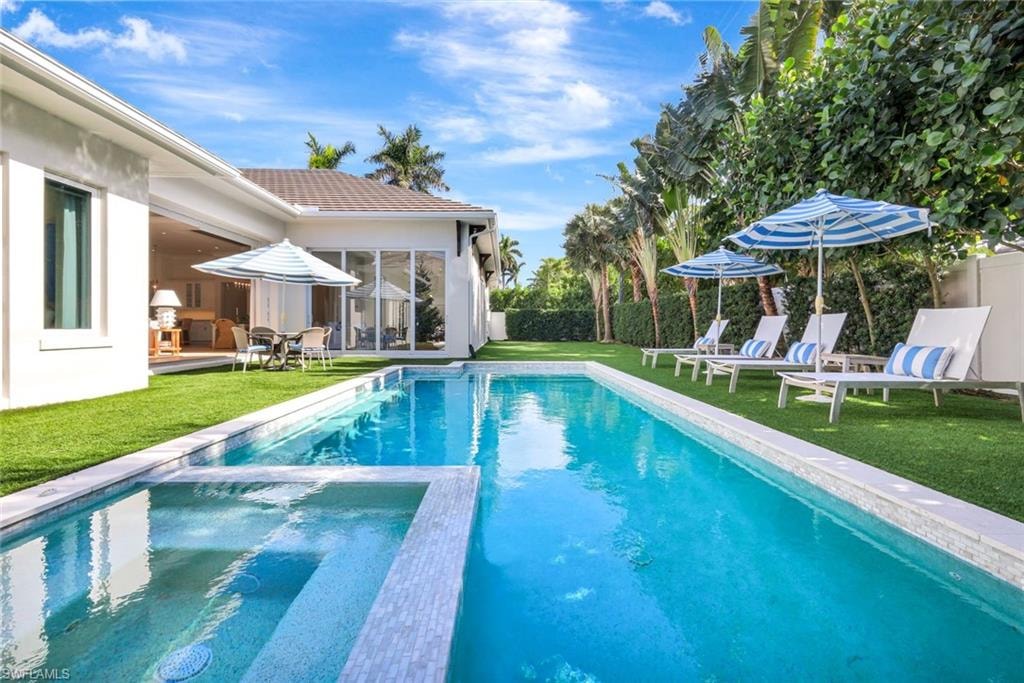 View of pool with a patio area, a pool with connected hot tub, and a sunroom