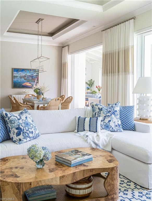 Living room featuring crown molding, a chandelier, and a tray ceiling