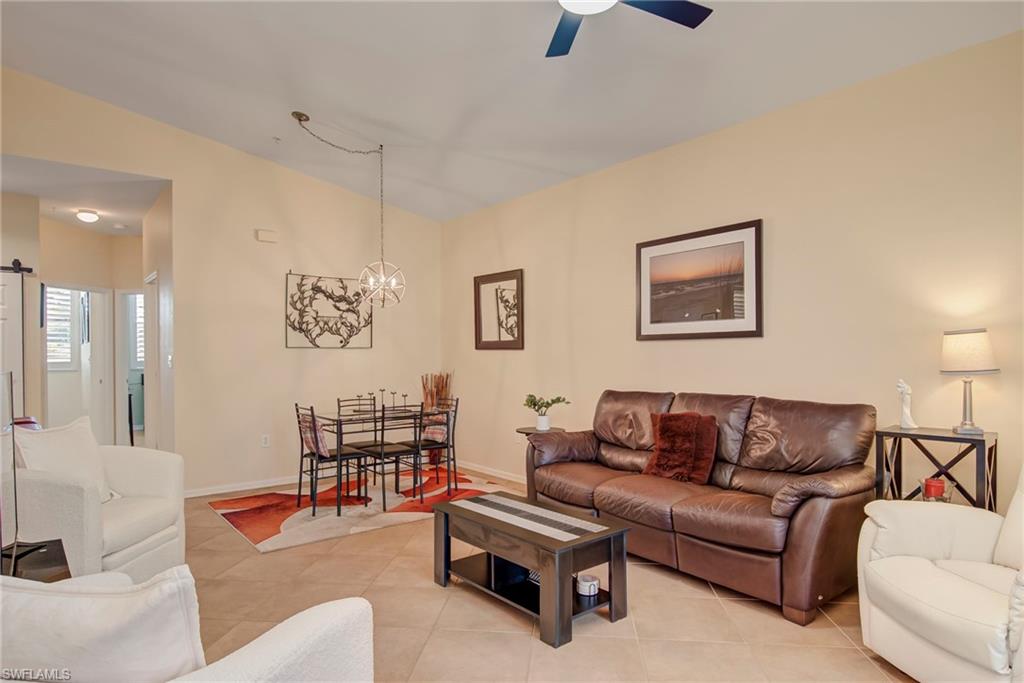 Living room featuring lofted ceiling, light tile patterned floors, and a chandelier