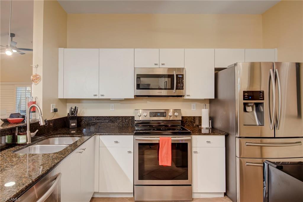 Kitchen featuring appliances with stainless steel finishes, dark stone countertops, and white cabinetry