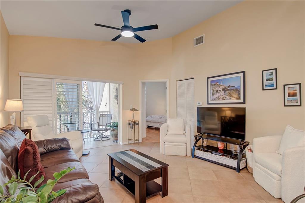 Living area with light tile patterned floors, a ceiling fan, and a high ceiling