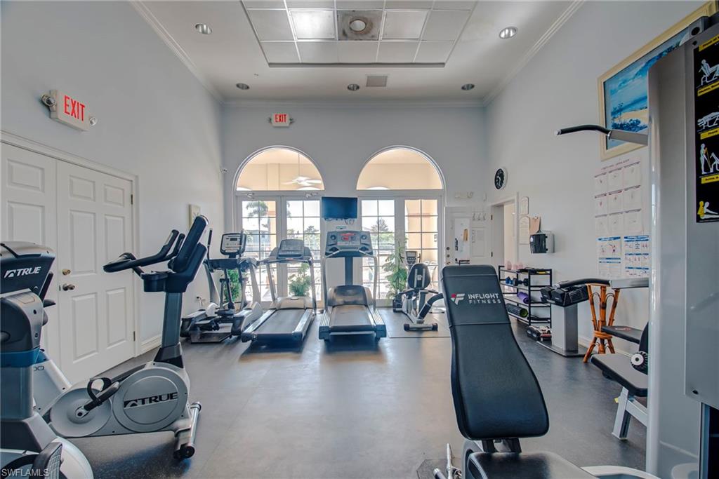 Gym with ornamental molding and a towering ceiling