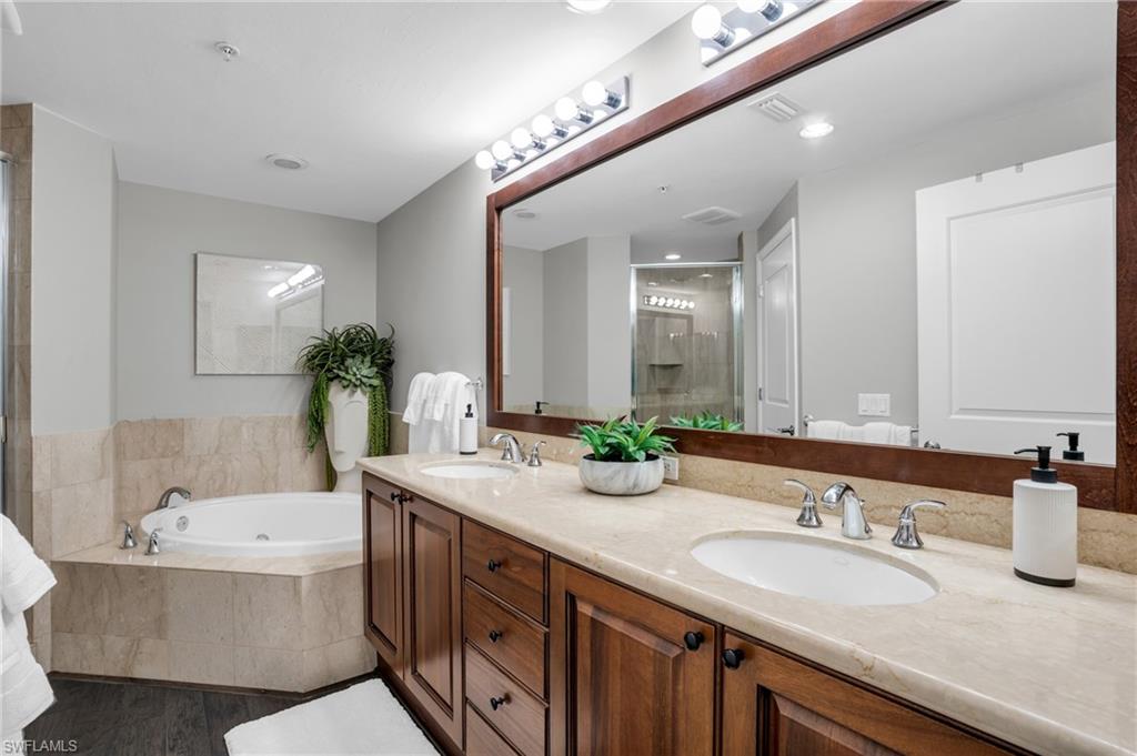 Full bath with double vanity, a garden tub, a stall shower, and dark wood-type flooring