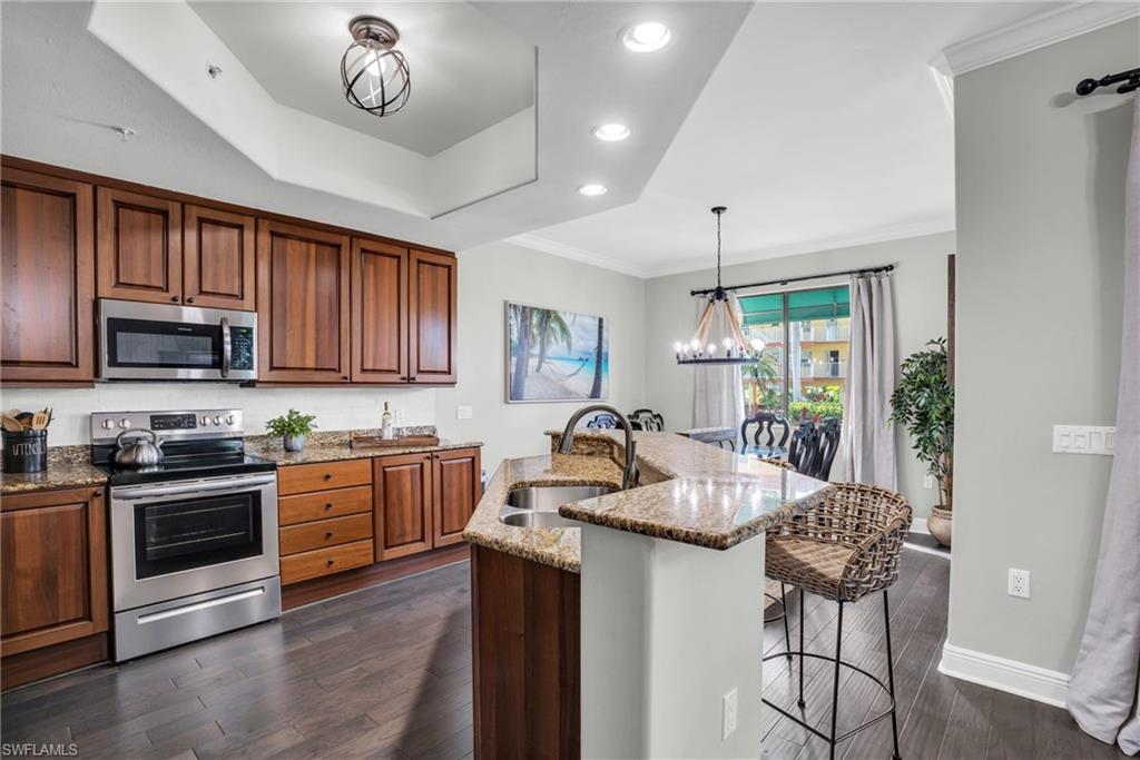 Kitchen featuring a chandelier, appliances with stainless steel finishes, recessed lighting, light stone countertops, and crown molding