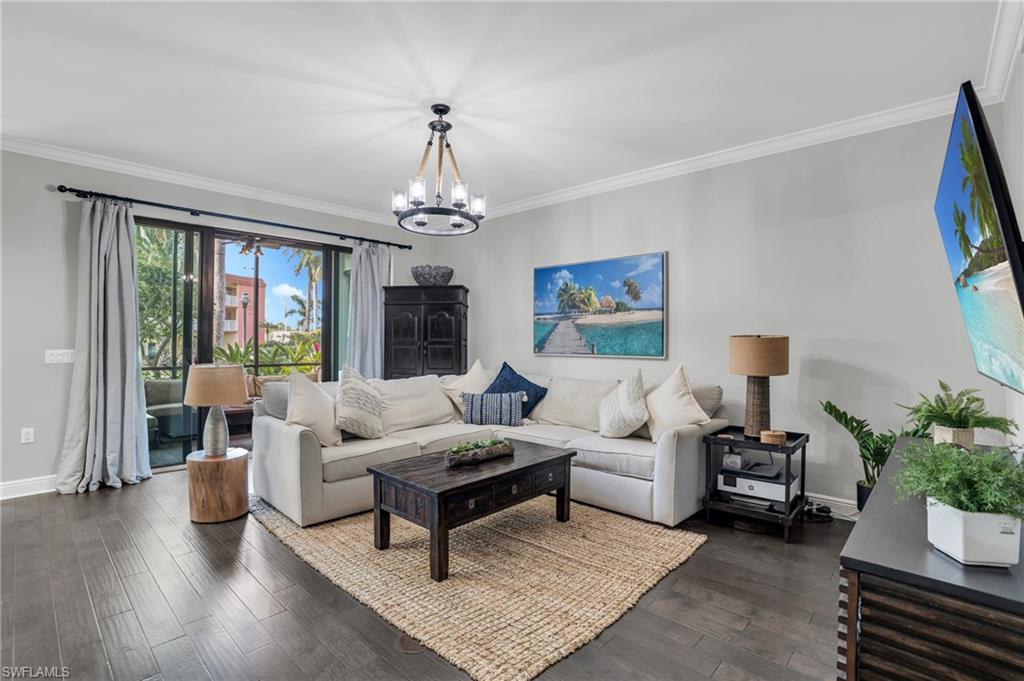 Living room featuring ornamental molding, dark wood-style floors, and a chandelier