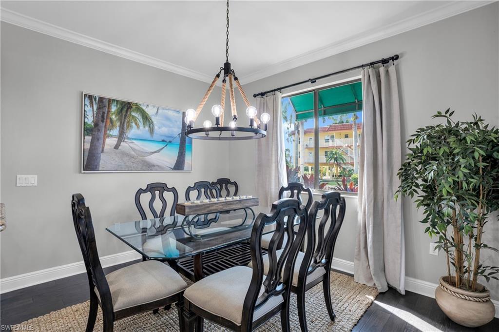 Dining room featuring ornamental molding, a chandelier, and dark wood-style flooring