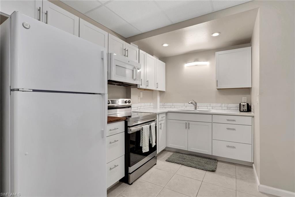 1/1 Efficiency-Kitchen with white appliances, white cabinets, light tile patterned floors, and recessed lighting